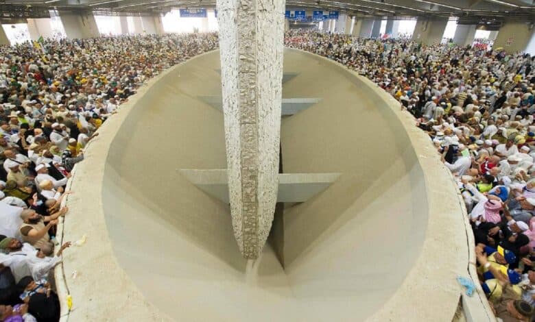 A large crowd of Haj pilgrims gathers around the Jamarat pillars in a spacious indoor area, performing the ritual of stoning the devil on June 6, 2025.