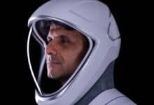 The image of a Indian astronaut Shubhanshu Shukla in a white space helmet, facing left, against a black background.