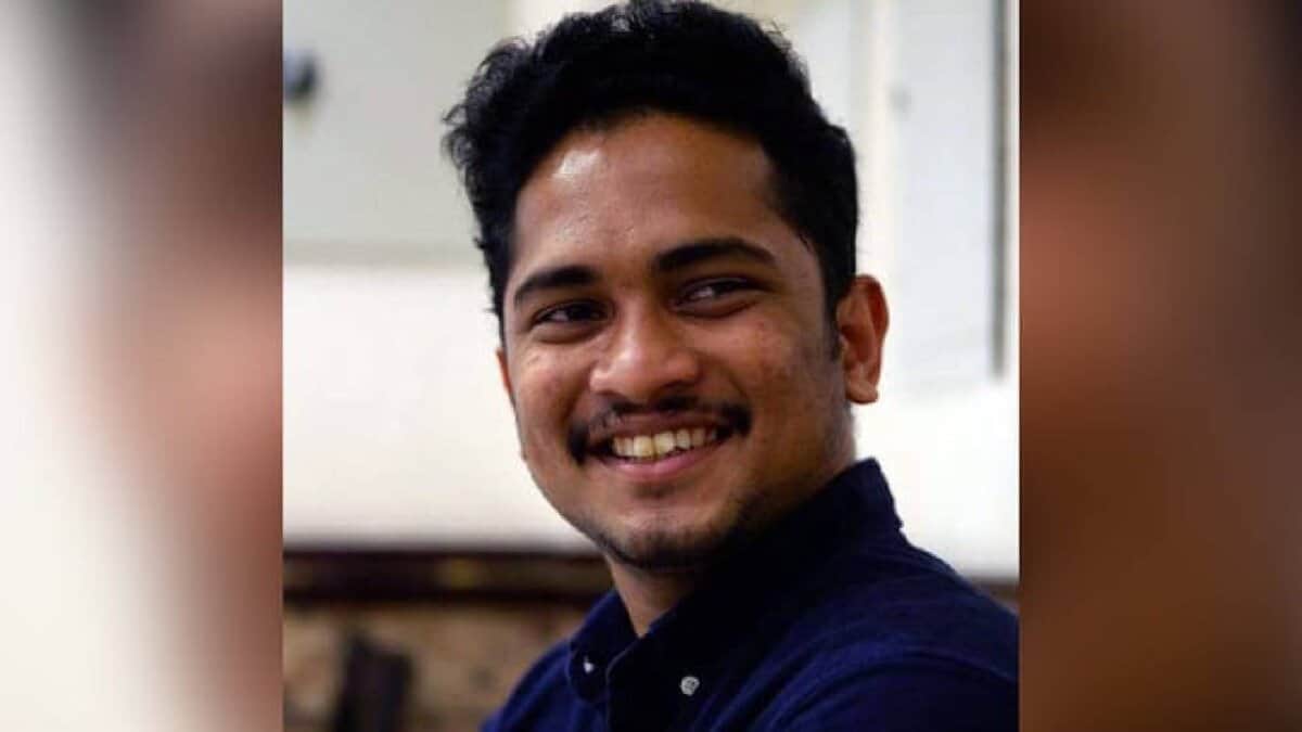 The image of 29-year-old Issac Paul Olakkengil, smiling and wearing a dark blue shirt, seated indoors.
