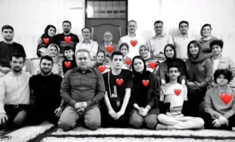 The image of a black-and-white group photo of 12 people, including men, women, and children, sitting and standing on a patterned rug, with red heart symbols overlaid on each person, symbolising their loss in a tragic airstrike.