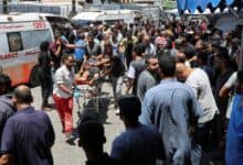Palestinians rush a wounded person on a stretcher through a crowded area outside a hospital in Gaza after an Israeli airstrike.
