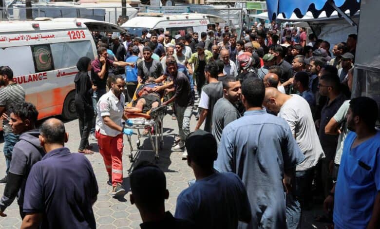 Palestinians rush a wounded person on a stretcher through a crowded area outside a hospital in Gaza after an Israeli airstrike.