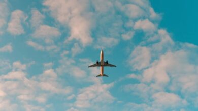 An aeroplane flying overhead against a blue sky with scattered white clouds.