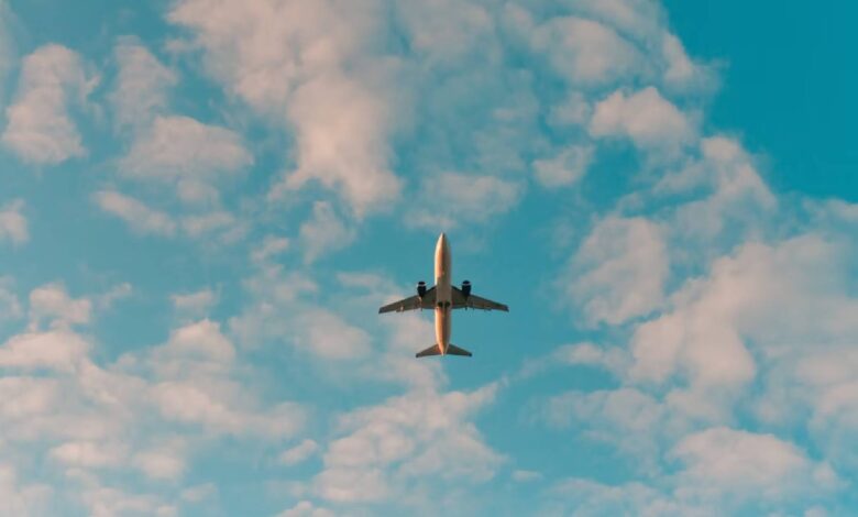 An aeroplane flying overhead against a blue sky with scattered white clouds.