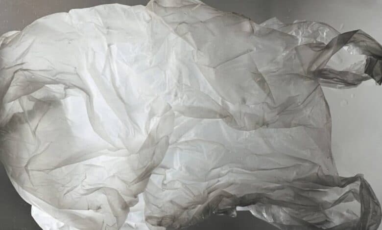 The image of a crumpled, translucent plastic bag floats against a blurred grey background.