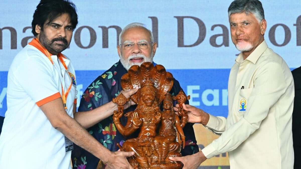 PM Modi with Andhra Pradesh CM Chandrababu Naidu and DyCM Pawan Kalyan holding a wooden idol at an event for #IDY2025.