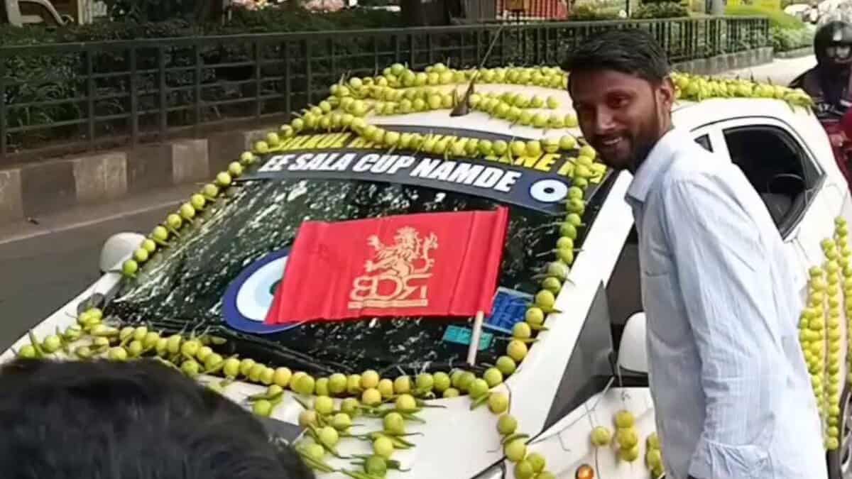 RCB fan poses next to car deocrated with Nimbu mirchi ahead of ipl final