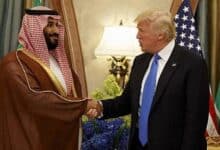 The image of Saudi Crown Prince Mohammed bin Salman shakes hands with US President Donald Trump during a meeting, with Saudi and US flags in the background.