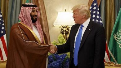 The image of Saudi Crown Prince Mohammed bin Salman shakes hands with US President Donald Trump during a meeting, with Saudi and US flags in the background.
