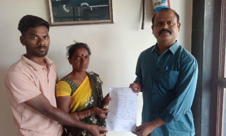 The image of a Lasmanna's family members handing over a written petition to Swadesh Parikipandla (right), a member of the Telangana State NRI Advisory Committee, seeking help to bring Lasmanna back from Dubai. They are standing indoors, holding the document together.