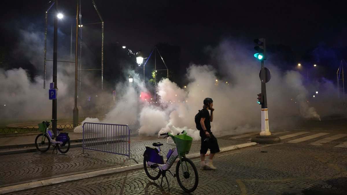 A man walks past tear gas during incidents after the Champions League final soccer match between Paris Saint-Germain and Inter Milan on Sunday in Paris.