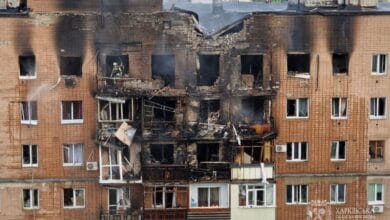 The image displays a picture of a burnt building in Ukraine's Kharkiv city