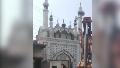 The image displays a Faridabad authorities trying to demolish a local mosque wall