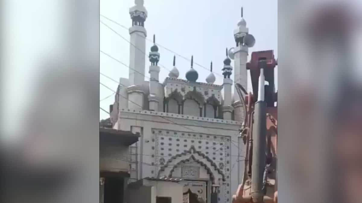 The image displays a Faridabad authorities trying to demolish a local mosque wall