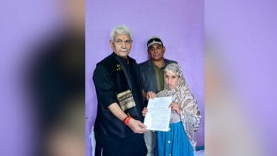The image displays a picture of J-K Lieutenant Governor Manoj Sinha handing over the appointment letter to Adil Shah’s wife, Gulnaz Akhter