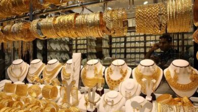 Gold jewellery shop in Dubai Gold Souk showcasing ornate bangles, necklaces and sets; shopkeeper visible in background.