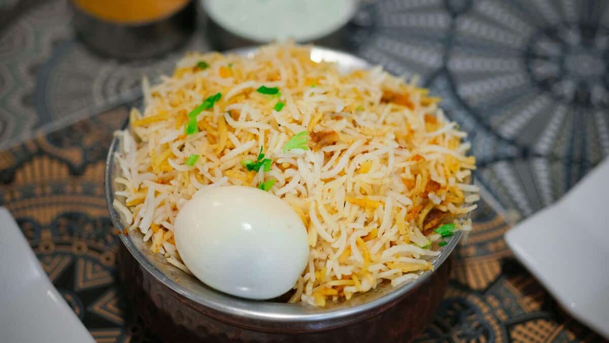 The image displays a picture of biryani with an egg