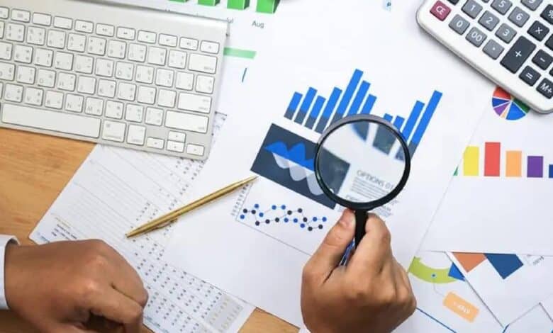 Representative image of financial data analysis with charts and magnifying glass.