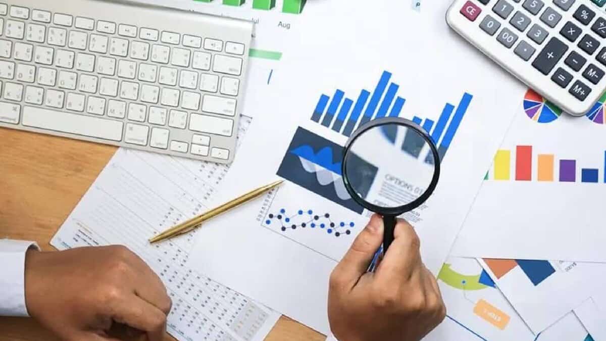 Representative image of financial data analysis with charts and magnifying glass.