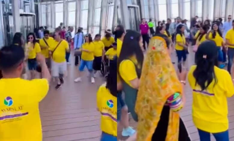 The image of a group of Indian tourists wearing matching yellow T-shirts dance Garba on the viewing deck of the Burj Khalifa in Dubai, as other visitors look on.