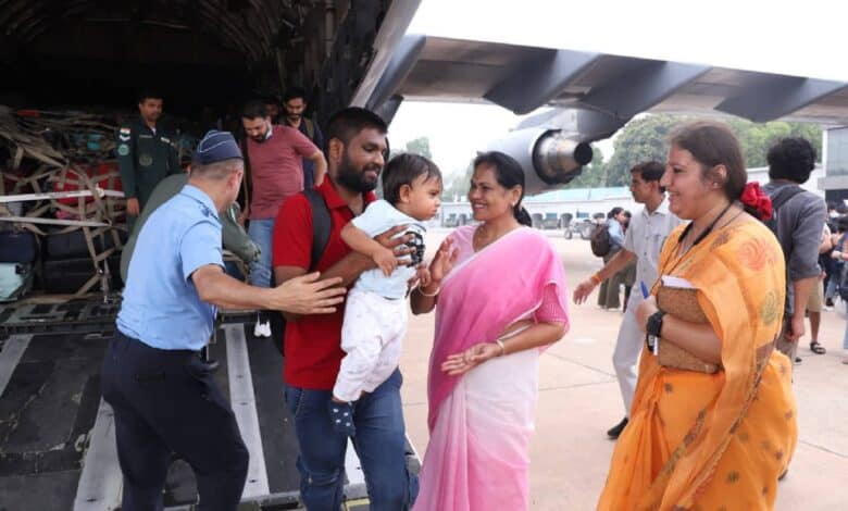 Minister Shobha Karandlaje welcomes Indian evacuees, including a man holding a child, arriving from Israel on an IAF aircraft under Operation Sindhu.