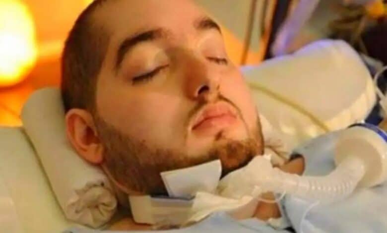 The image of a Prince Al-Waleed bin Khaled bin Talal, known as the Sleeping Prince, lies in a hospital bed with his eyes closed, supported by a ventilator tube attached at his neck.