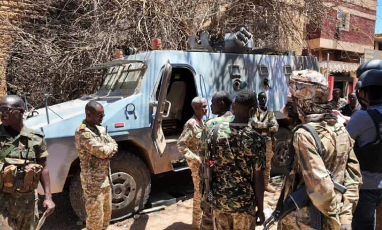 Sudanese army soldiers stand near a damaged armoured vehicle after clashes with the Rapid Support Forces (RSF) in Khartoum.