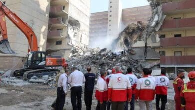 Rescuers search through debris at the site of a damaged building following Israeli strikes in Tehran, Iran, on June 13, 2025. The building shows severe structural damage, with rubble scattered around as emergency workers assess the scene.