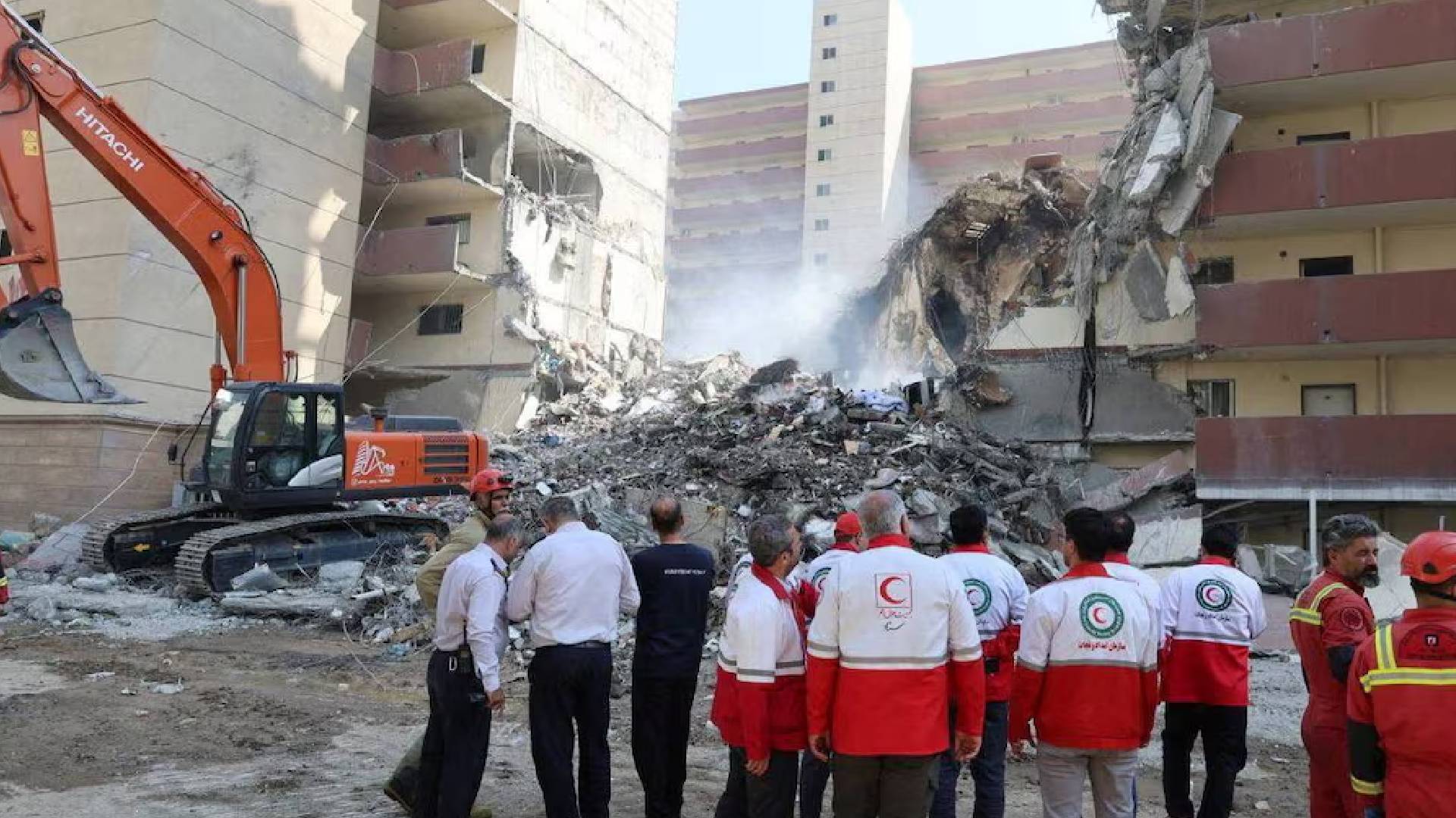 Rescuers search through debris at the site of a damaged building following Israeli strikes in Tehran, Iran, on June 13, 2025. The building shows severe structural damage, with rubble scattered around as emergency workers assess the scene.