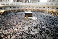 A large crowd of pilgrims gathers around the Kaaba inside the Masjid al-Haram in Makkah during Umrah. The mosque’s white marble flooring and arched colonnades surround the central black-draped structure as worshippers perform tawaf.