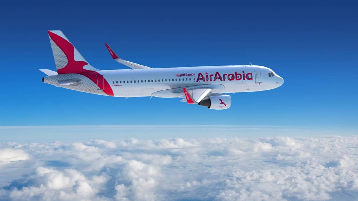 The image of Air Arabia Airbus A320 aircraft flying above the clouds with a clear blue sky in the background.
