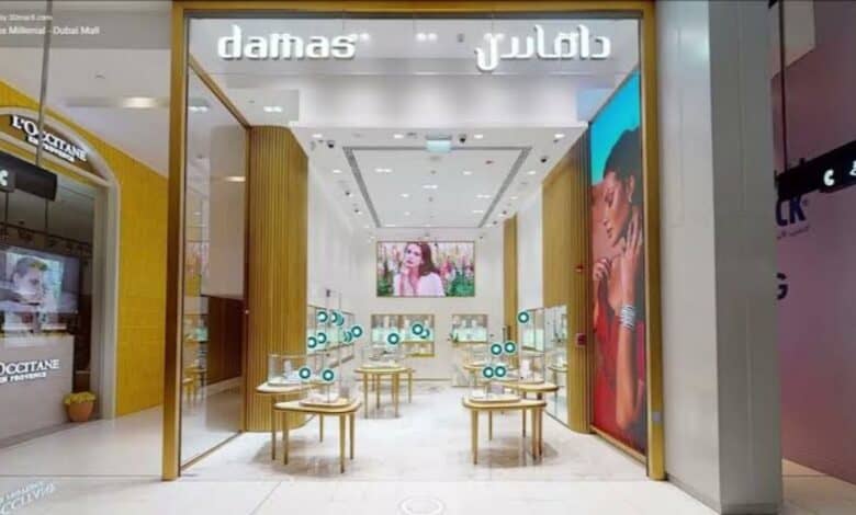 A modern Damas jewellery store in Dubai Mall, featuring sleek interiors, display tables with jewellery, and illuminated branding in English and Arabic.