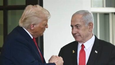 The image of Donald Trump on the left, wearing a dark suit with a red tie, shaking hands with Benjamin Netanyahu on the right, wearing a black suit with a red tie and a small flag pin, standing in front of a white building with large windows.