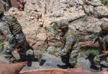 The image of Turkish soldiers in combat gear patrol a rocky terrain near a military outpost, demonstrating operational readiness in a mountainous border region.