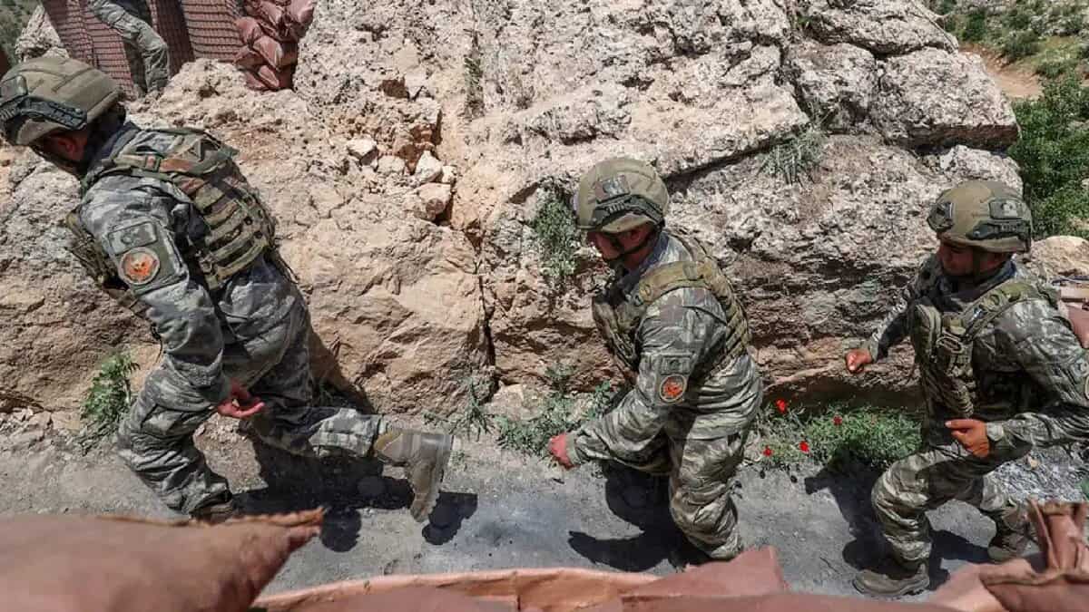 The image of Turkish soldiers in combat gear patrol a rocky terrain near a military outpost, demonstrating operational readiness in a mountainous border region.