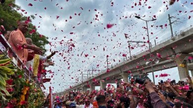 Uttar Pradesh Chief Minister Yogi Adityanath showers flower petals on 'Kanwariyas' during their pilgrimage in the holy month of 'Shravan' in Meerut on Sunday. (PTI Photo)