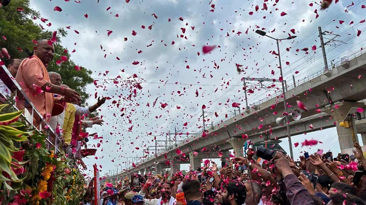 Uttar Pradesh Chief Minister Yogi Adityanath showers flower petals on 'Kanwariyas' during their pilgrimage in the holy month of 'Shravan' in Meerut on Sunday. (PTI Photo)