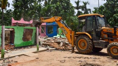 A bulldozer razes down a house from the Paikan Reserve Forest area in Assam's Goalpara district (PTI Photo)