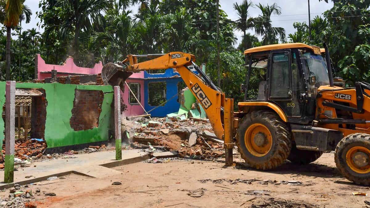 A bulldozer razes down a house from the Paikan Reserve Forest area in Assam's Goalpara district (PTI Photo)