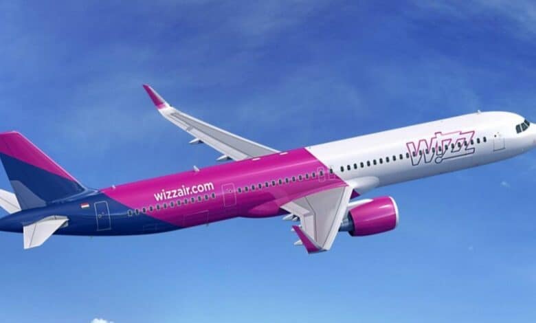A Wizz Air passenger aircraft in flight against a clear blue sky.