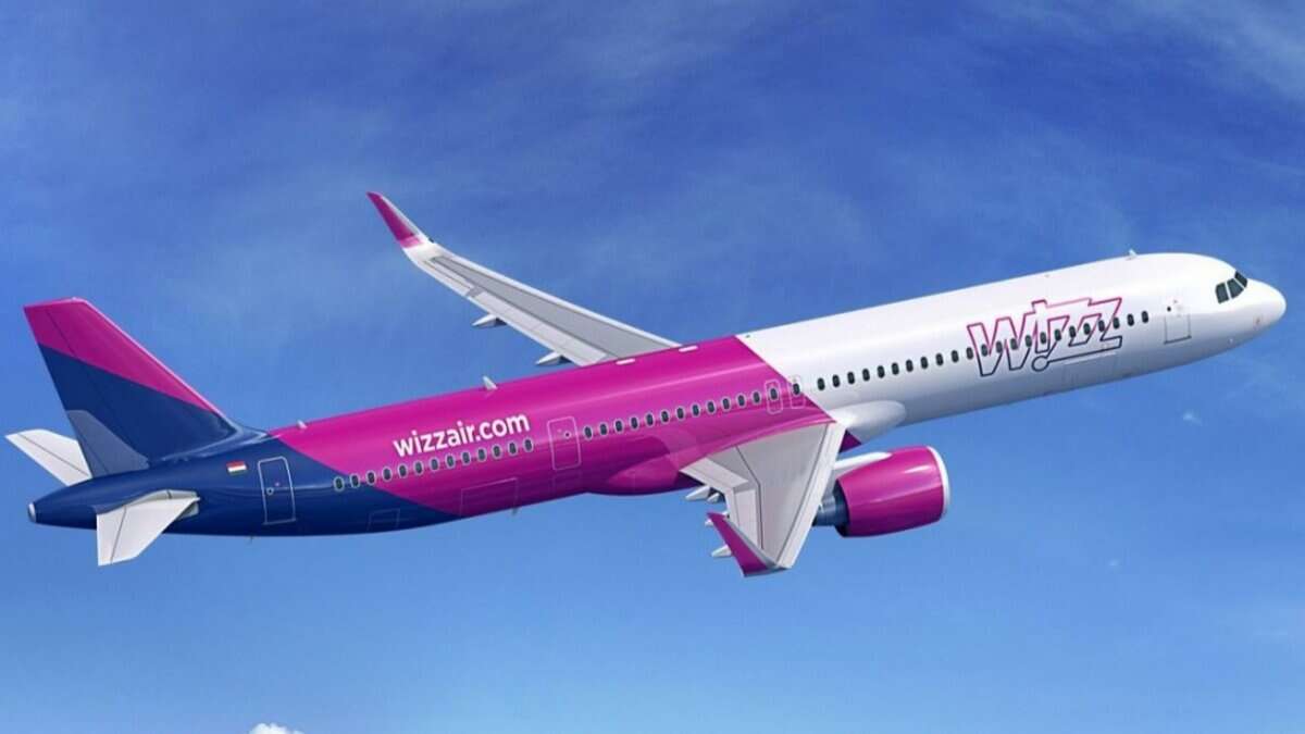 A Wizz Air passenger aircraft in flight against a clear blue sky.