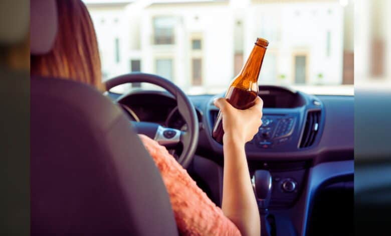 A woman driving with a bottle in hand