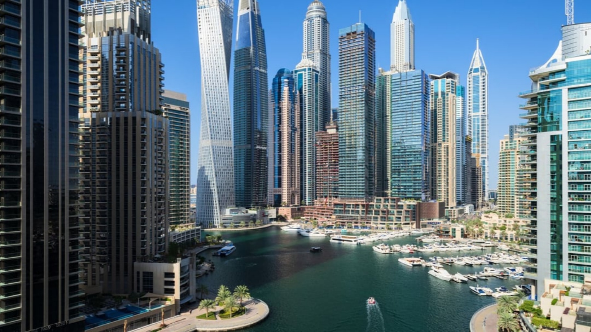 Dubai Marina skyline with modern high-rise buildings and yachts docked along the waterfront.