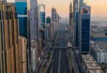 Aerial view of Sheikh Zayed Road in Dubai lined with supertall skyscrapers on both sides during sunset.
