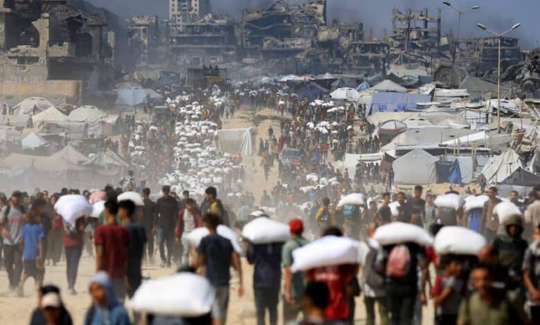 Palestinians carry aid packages through a crowded street in Beit Lahia, northern Gaza, on July 20, 2025, amid a worsening hunger crisis.
