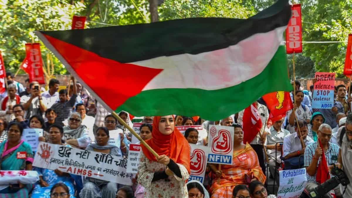 Woman waves Palestinian flag at Gaza ceasefire protest in New Delhi.
