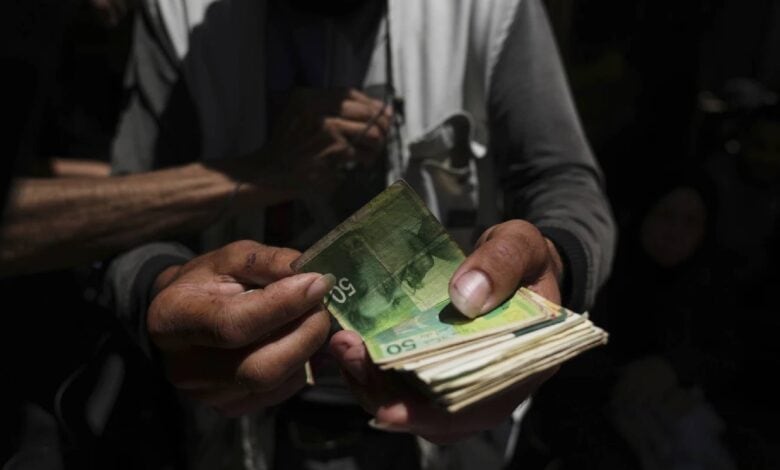 A Palestinian vegetable merchant holds worn-out Israeli banknotes in Gaza City on July 9, 2025, highlighting the cash crisis affecting daily trade in the war-torn territory.