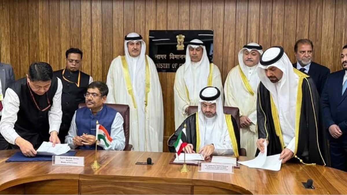 Officials from India and Kuwait sign a bilateral air services agreement in New Delhi, seated at a wooden conference table with national flags and nameplates.