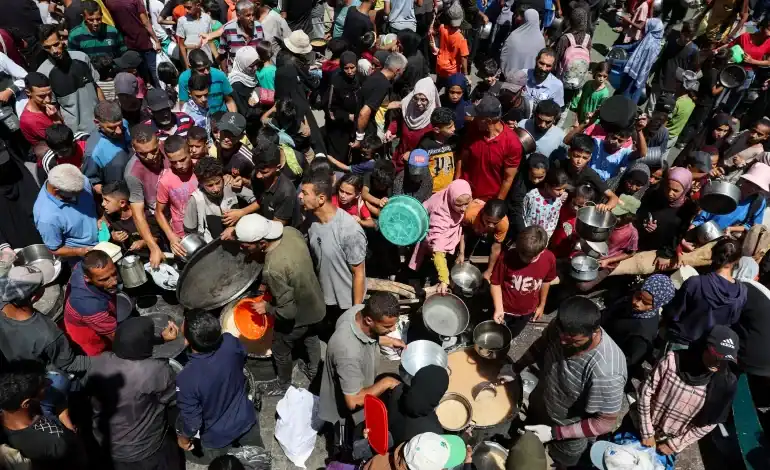 A crowded scene of Palestinians receiving food from a charity kitchen in Nuseirat, Gaza, amid a hunger crisis, July 20, 2025.