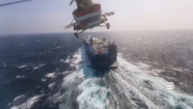 A cargo ship ablaze in the Red Sea after an aerial attack, smoke billowing from the vessel as nearby waters reflect the fire.